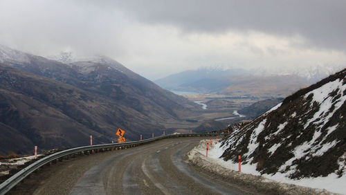 Road leading towards snowcapped mountains against sky