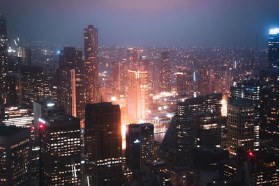 Illuminated cityscape against sky at night