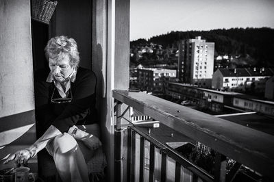 Senior woman sitting by railing on balcony
