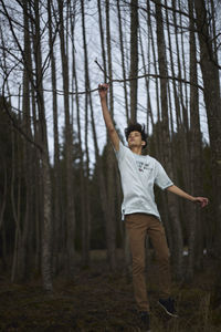 Full length of young woman jumping in forest