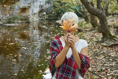 Woman with umbrella standing against trees