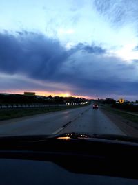 Car on road against cloudy sky during sunset