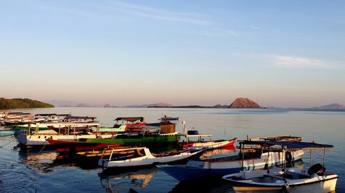 Boats moored at harbor against sky during sunset