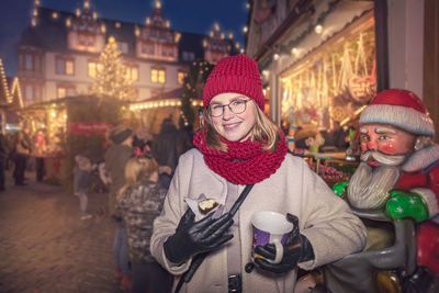 Portrait of young woman standing in market during christmas