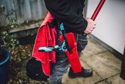 Low section of person holding red umbrella standing outdoors