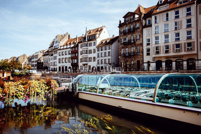 Bridge over river by buildings in city against sky