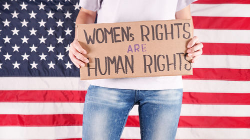 Woman holding sign women rights are human rights against american flag 