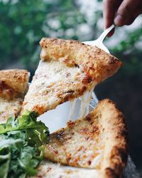 Cropped hand of woman holding pizza slice with server