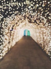 Low section of woman walking in illuminated corridor