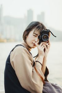 Close-up of girl holding camera against sea