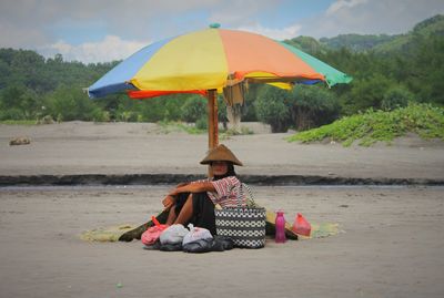 Woman with umbrella at beach against sky