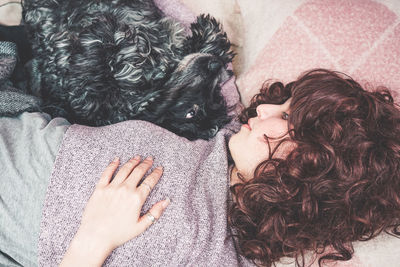 Woman with dog lying on bed at home