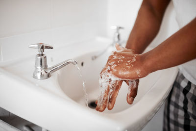 Cropped hand washing hands in sink