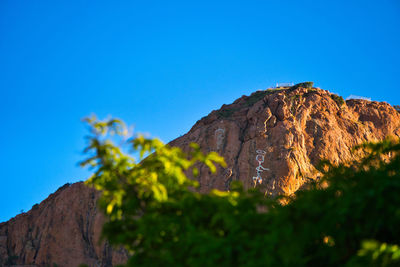Low angle view of rock formation against clear blue sky
