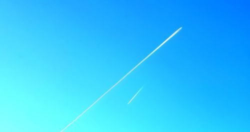 Low angle view of vapor trail against clear blue sky