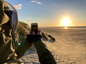 Man photographing at beach during sunset