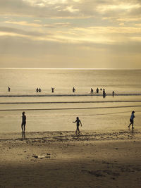 Silhouette people at beach against sky during sunset