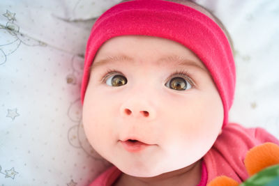 Close-up portrait of cute baby girl lying on bed at home