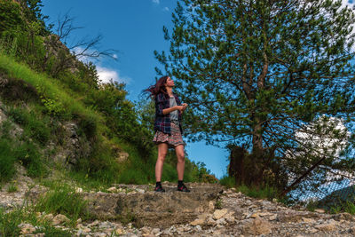 Woman standing by trees against sky