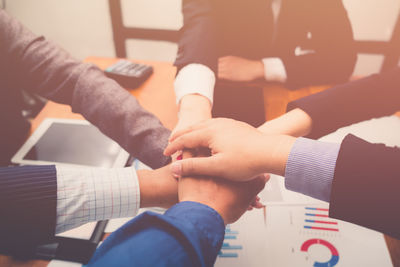 High angle view of colleagues stacking hands over desk