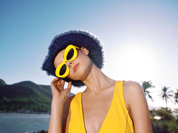 Portrait of young woman wearing hat against sky