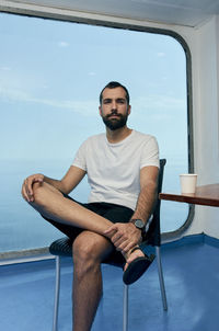 Young man looking away while sitting on seat