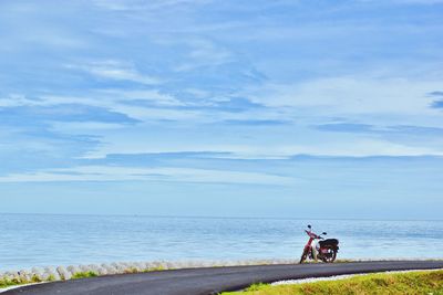 People riding bicycle on beach against sky