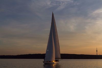 Sailboat sailing in sea at sunset