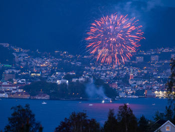 Firework display over illuminated city against sky at night