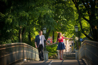 Woman showing something to man while standing on footbridge at public park