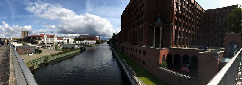 Panoramic view of canal in city against sky