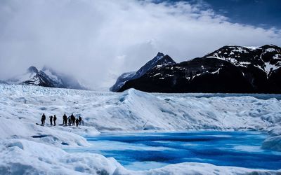 Hikers at perito moreno glacier against sky