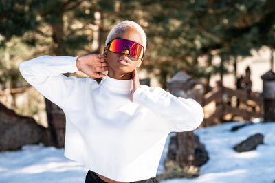 A young african american woman wearing sunglasses having fun in the snow on a winter day