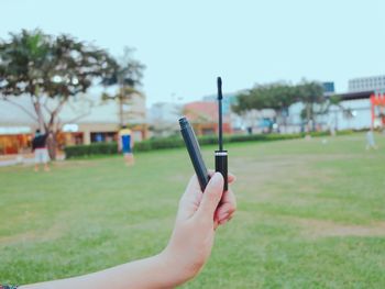 Close-up of hand holding mobile phone on grass