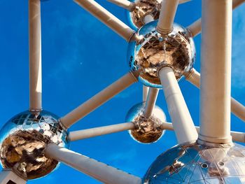 Low angle view of lighting equipment hanging against blue sky