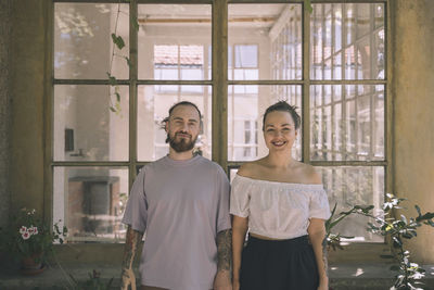 Smiling boyfriend and girlfriend standing in front of window