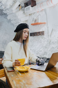 Young woman using mobile phone while sitting on table