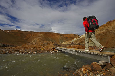 Hiker crossing wooden bridge in the icelandic highlands