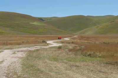 Scenic view of road amidst field against sky