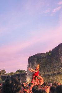 People on rock against sky during sunset