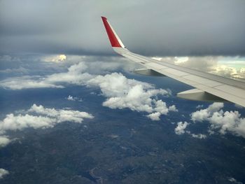 Airplane wing over clouds against sky