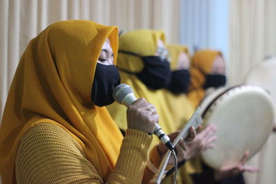 Women wearing masks and traditional clothing performing in event