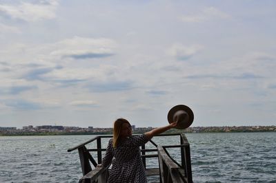 Rear view of woman photographing against sea