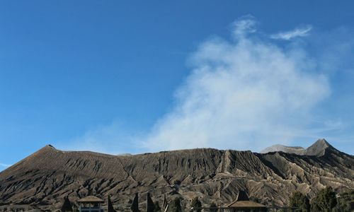 Scenic view of volcanic mountain against blue sky