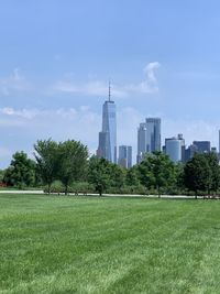 Scenic view of field by buildings against sky