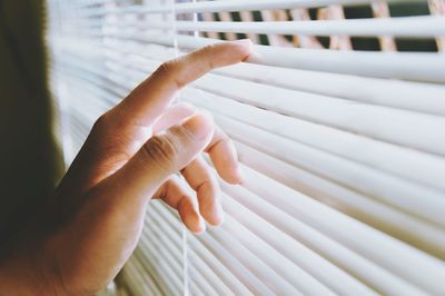 Cropped hand touching window blinds