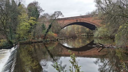 Arch bridge over river against sky