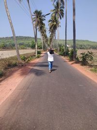 Rear view of man walking on road