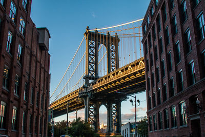 Low angle view of suspension bridge in city against sky