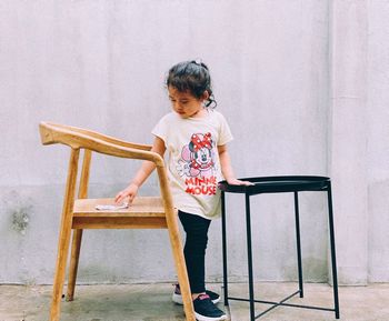 Boy standing on chair against wall